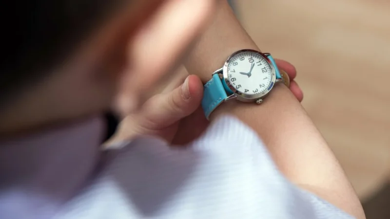 Junge schaut auf seine Armbanduhr, Kinderuhr als Geschenk