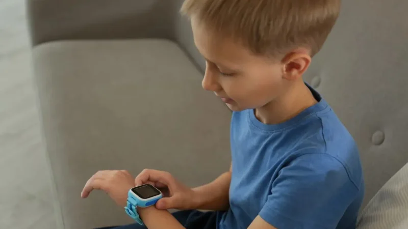 Junge mit Smartwatch am Handgelenk auf dem Sofa