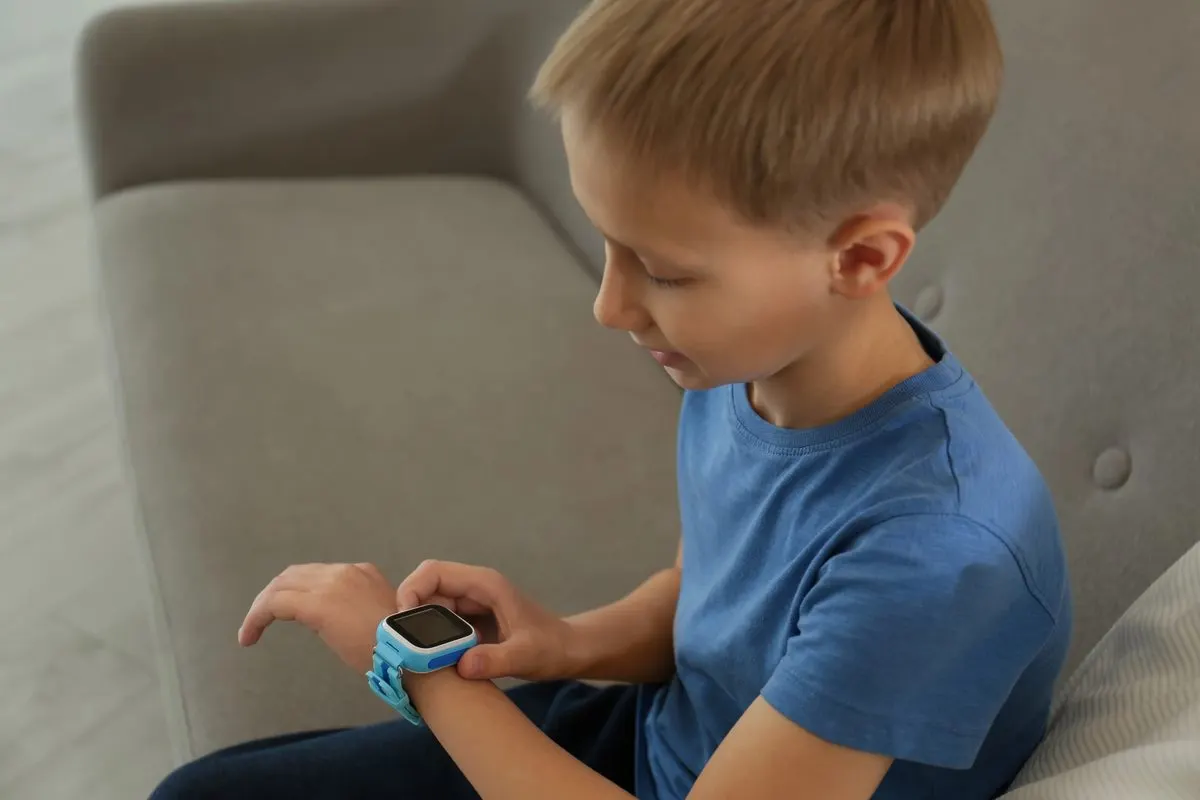 Junge mit Smartwatch am Handgelenk auf dem Sofa